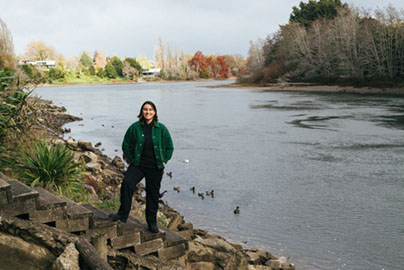 Danielle in front of the Waikato river, with ducks floating on the water